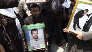 Jader Adnan (c), miembro histórico de la Yihad islámica, aparece sentado en la fotografía, sosteniendo el retrato de un preso durante una protesta. EFE/Alaa Badarneh