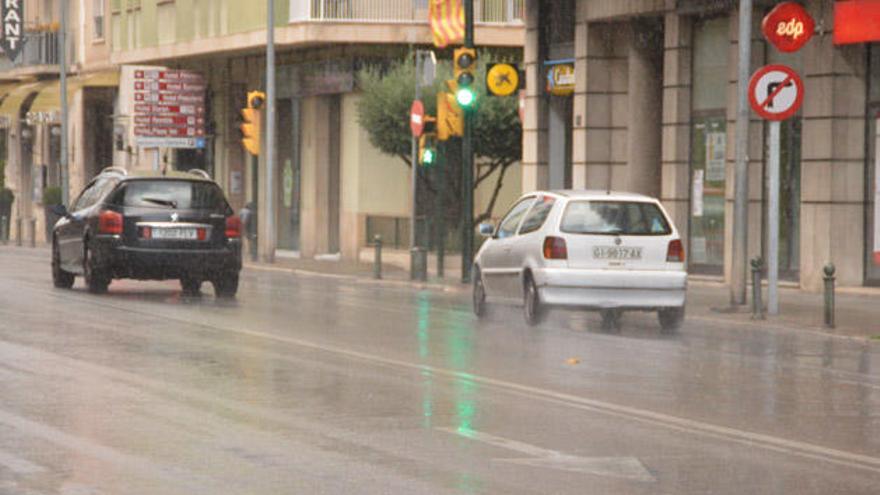 Vehicles circulant sota la pluja a Figueres.