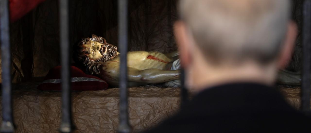 Un hombre mira la imagen de Jesús yacente en la iglesia de San Nicolás.