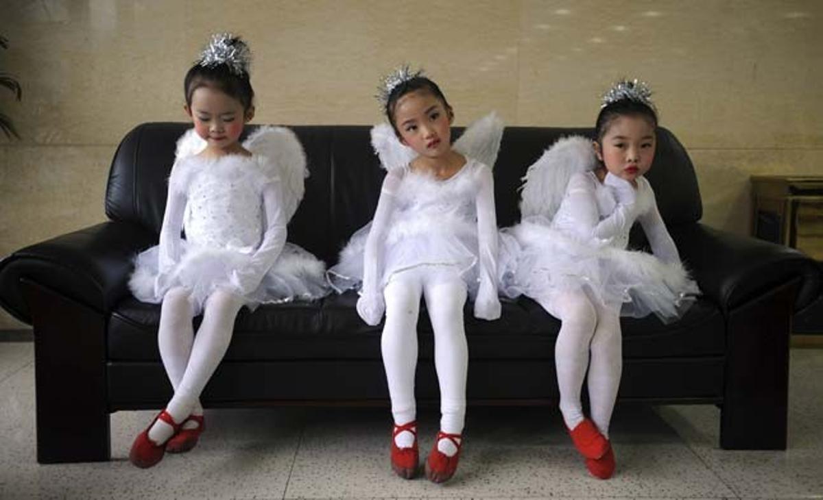 Tres nenes esperen abans d’actuar en un acte promocional a Kunming (Xina), on faran ballet.