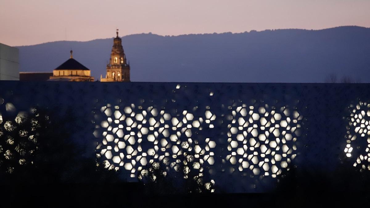 Fachada iluminada del C3A de Córdoba, con la torre de la Catedral al fondo