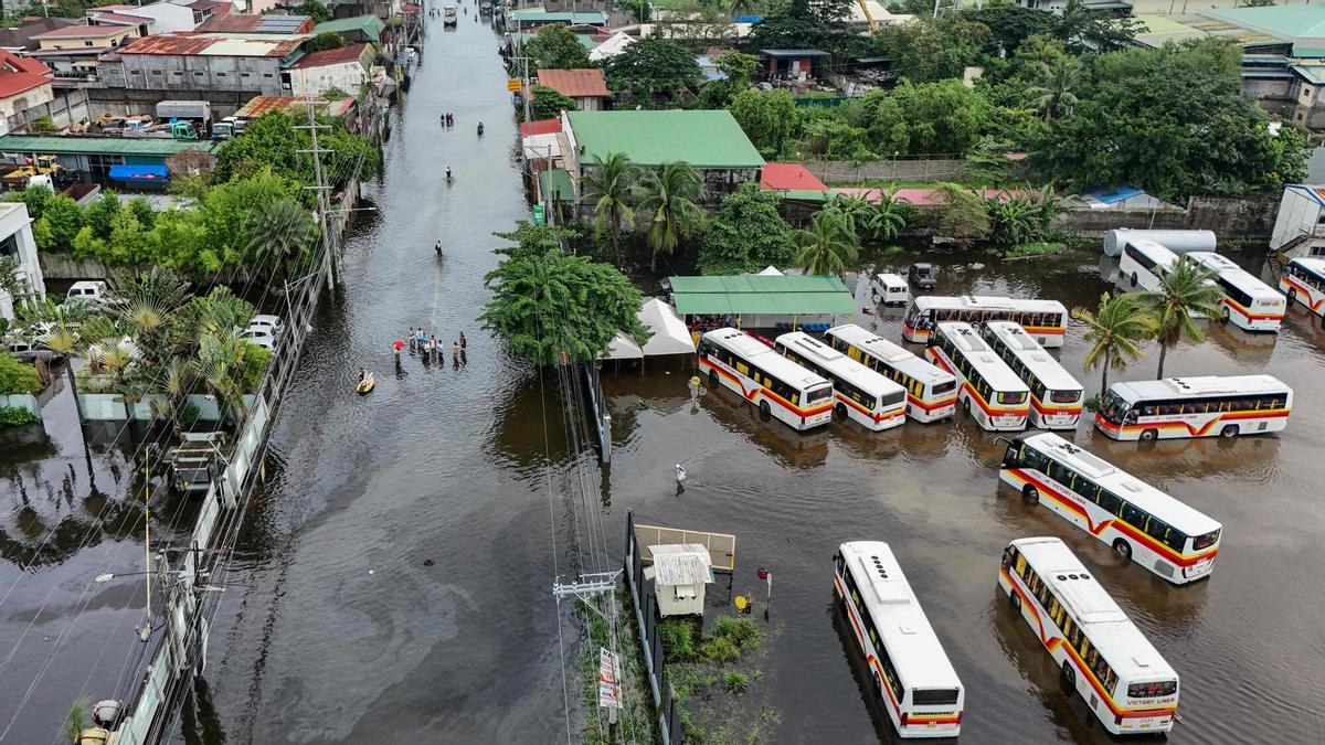 La gente camina a través de una calle inundada después de las fuertes lluvias traídas por el monzón del suroeste en Pampanga el 31 de agosto de 2026. (Foto de Jam STA ROSA / AFP)