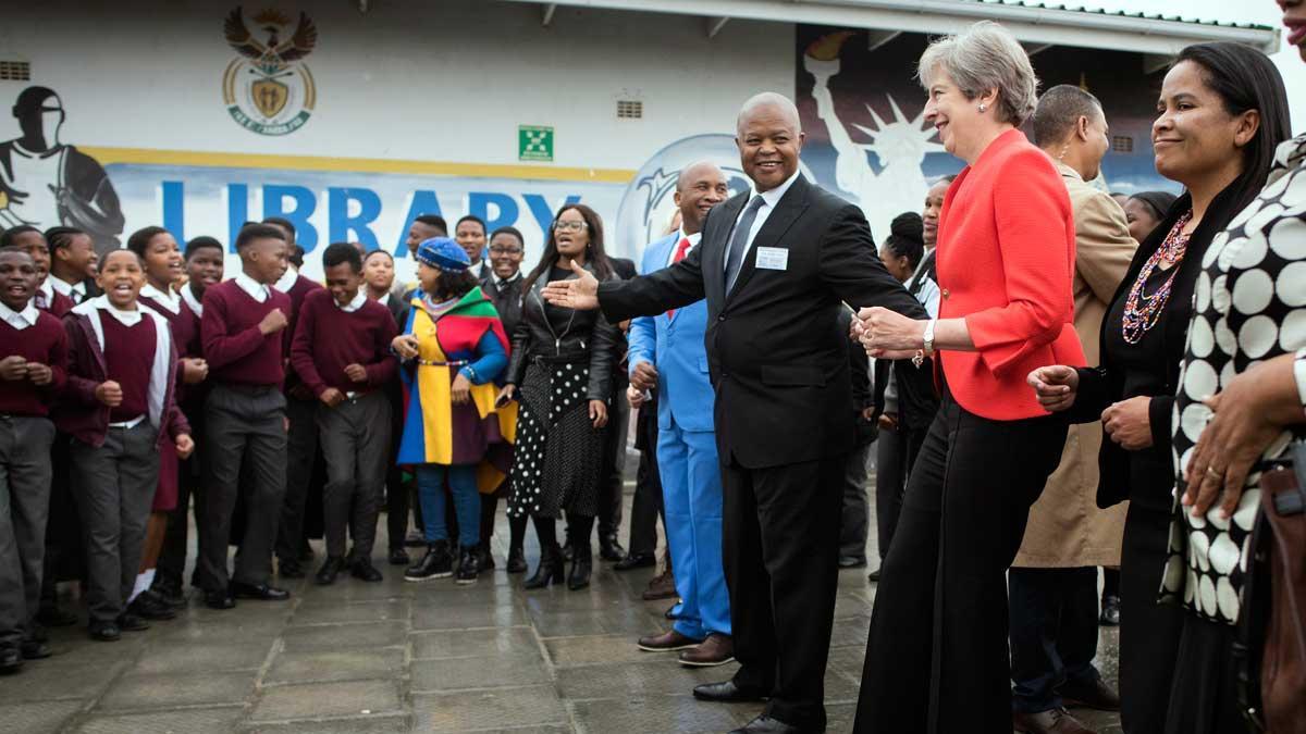 Theresa May baila con niños en su visita a Sudáfrica.