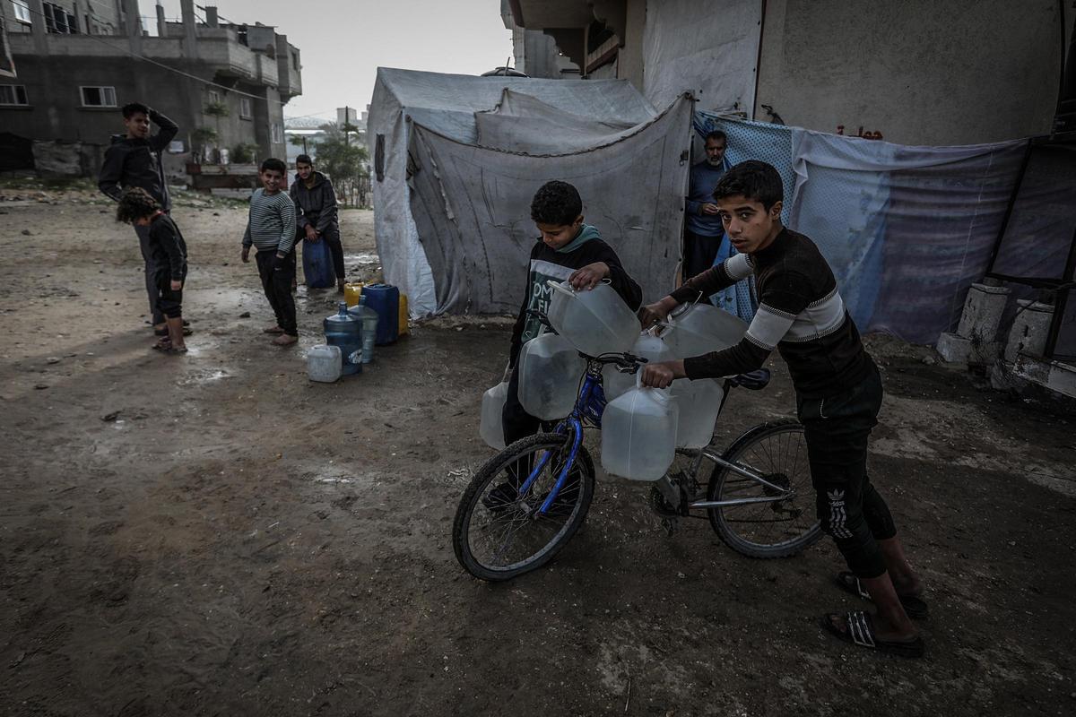 Niños palestinos con bidones de agua en Jan Yunes, en la Franja de Gaza