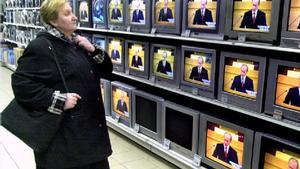 Una mujer mira monitores en una tienda de televisiones en San Petersburgo durante un discurso de Vladimir Putin