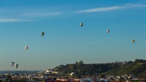 Los participantes en la regata de globos aerostáticos despegan al amanecer junto al puente del Quinto Centenario en la exhibición aérea que tiene lugar hoy en la antigua base aérea de Tablada en Sevilla para celebrar los 100 años de este aeródromo.