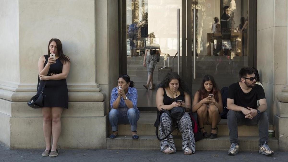 Personas hablando por el móvil en el paseo de Gràcia de Barcelona.