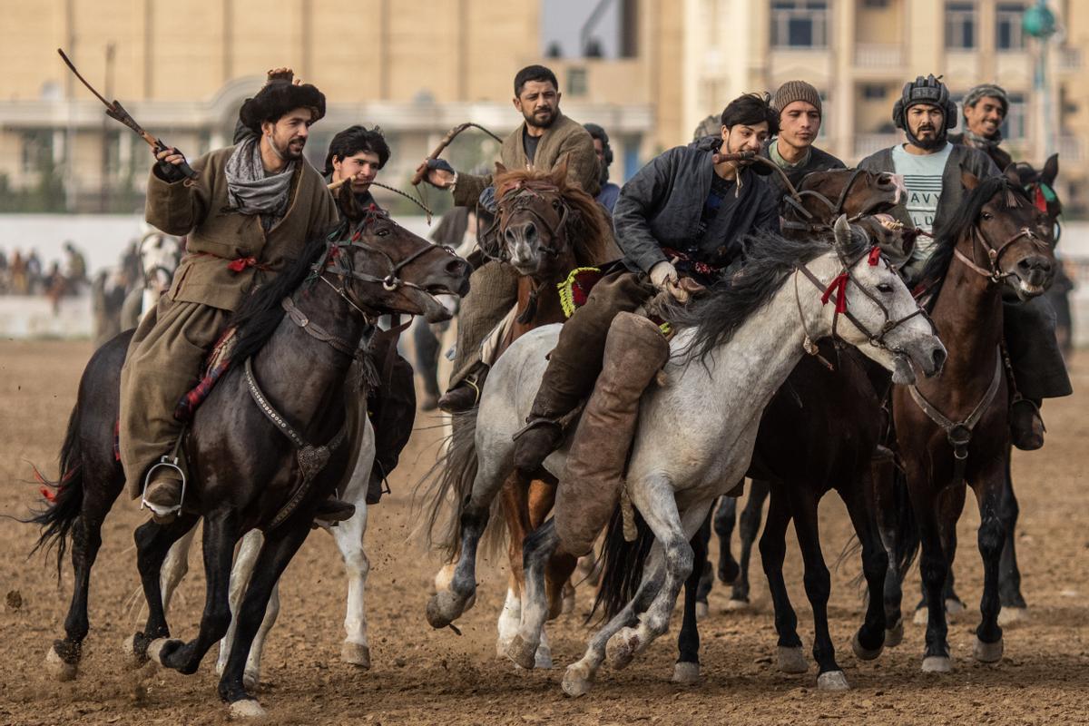 Jinetes afganos compiten en un deporte tradicional de Asia Central, en el que los jugadores montados a caballo intentan colocar una bolsa que se asemeja a un cadáver de cabra en una portería