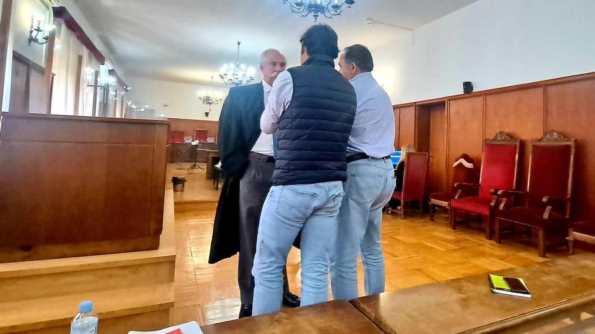 El exalcalde de Oliva de la Frontera, derecha, y el exarquitecto municipal, charlan con su abogado durante el receso en la Audiencia Provincial de Badajoz.