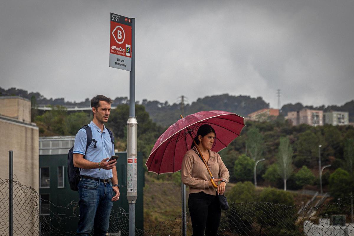 Dos usuarios del bus a demanda de Torre Baró esperan en una de las paradas del barrio