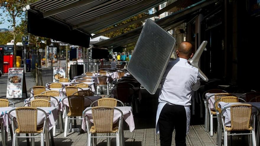 Un camarero recoge una mesa de una terraza de un restaurante del barrio de la Barceloneta.