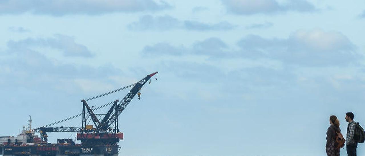 La grúa semisumergible &#039;SSCV Thialf&#039;, ayer ante la mirada de dos espectadores, maniobrando una de sus dos plumas durante su fondeo en la bahía de Las Palmas.