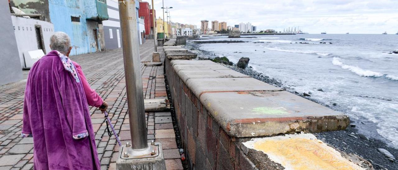 Una mujer camina por el paseo del barrio marinero de San Cristóbal