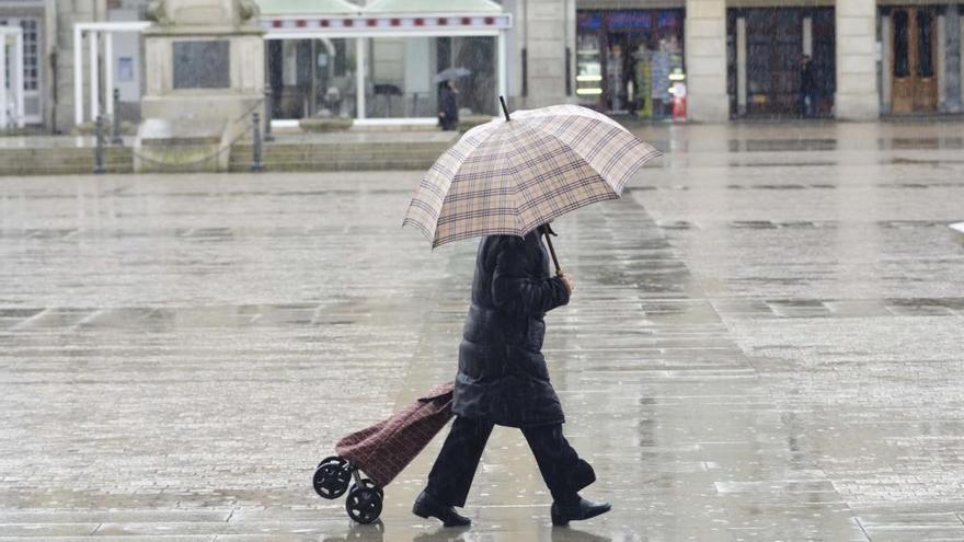 Una mujer se resguarda de la lluvia con un paraguas en la plaza de María Pita.