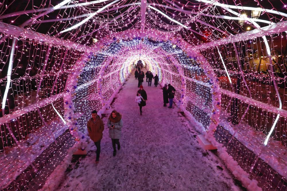 People walk under festive decorations for the ...