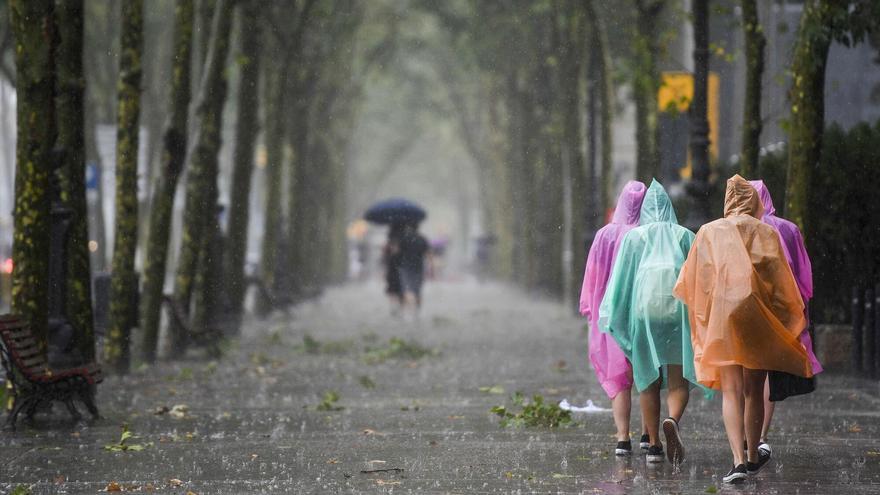 Paseantes protegidos de la lluvia caminan por la Diagonal.