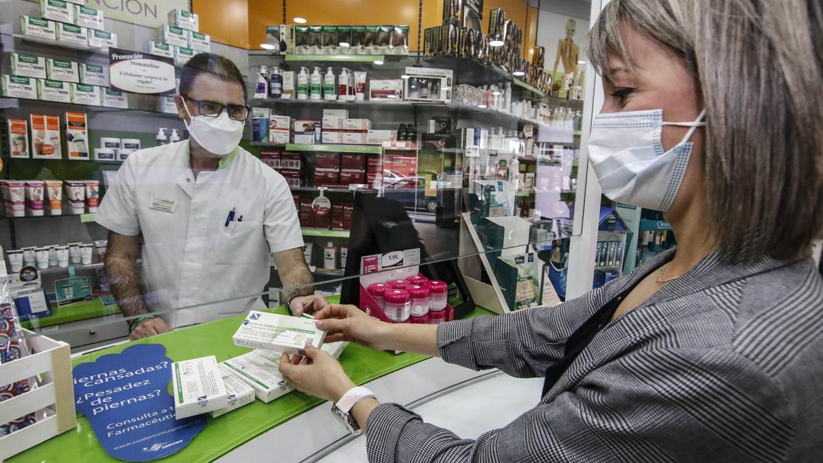 Una mujer compra test de antígenos en una farmacia de Cáceres.