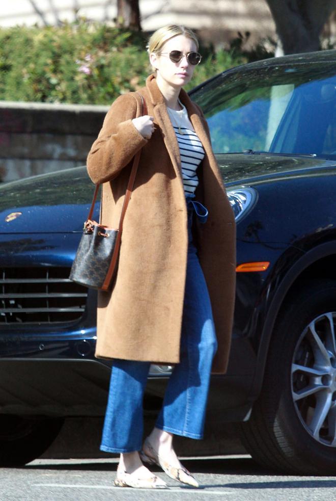 Emma Roberts con abrigo camel, vaqueros rectos y bolso Celine