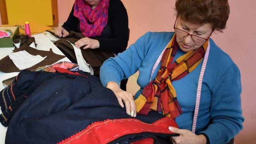 Dos mujeres durante la confección de trajes de forma manual.