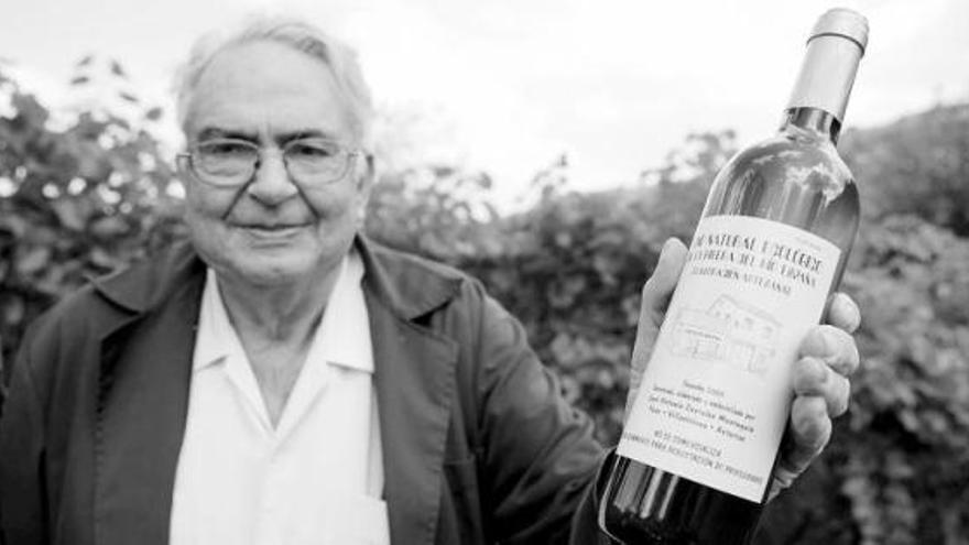 José Antonio Costales Montequín, «El Ténicu», muestra una botella de vino producido en su bodega.