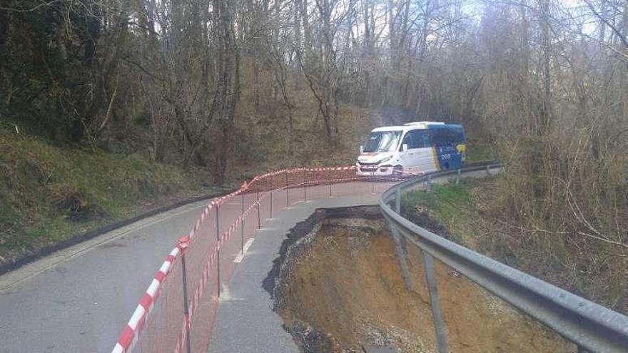 Un autobús escolar circula junto al argayo de la carretera de Güexes y Fíos.