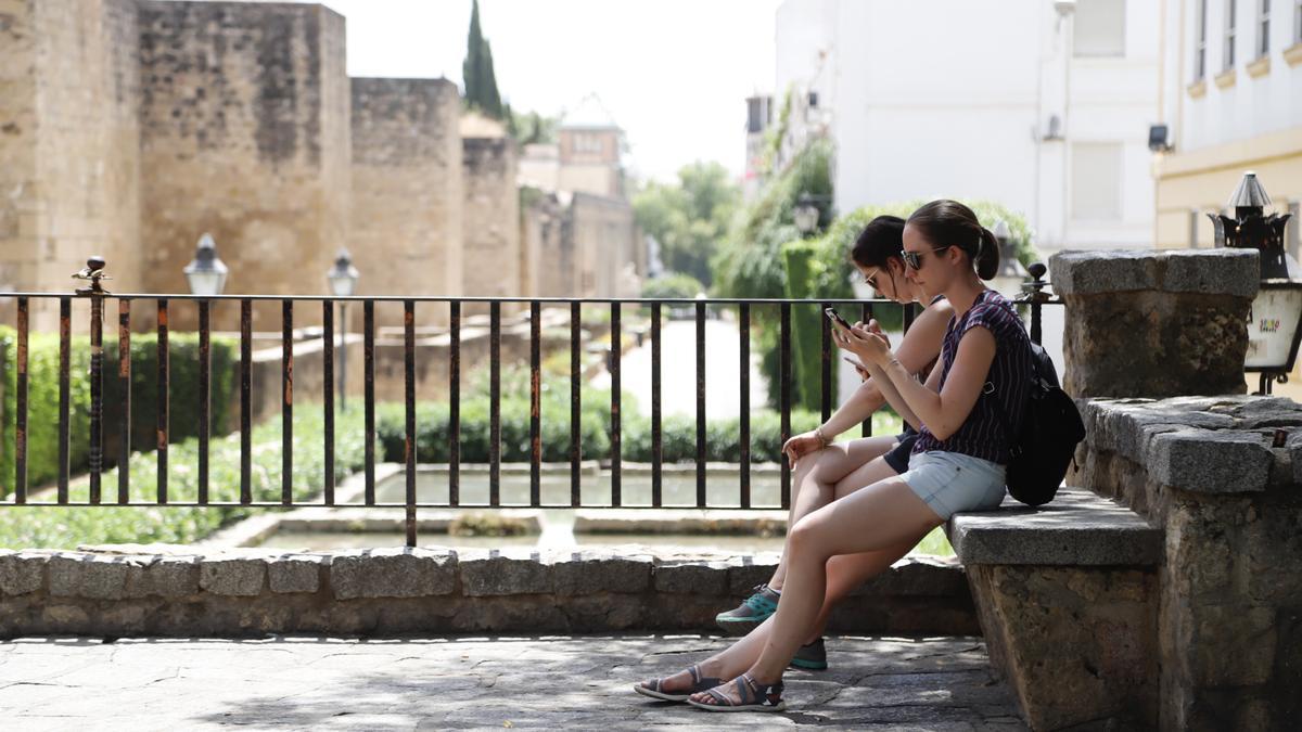 Dos turistas se refrescan a la sombra en una tarde estival cordobesa.