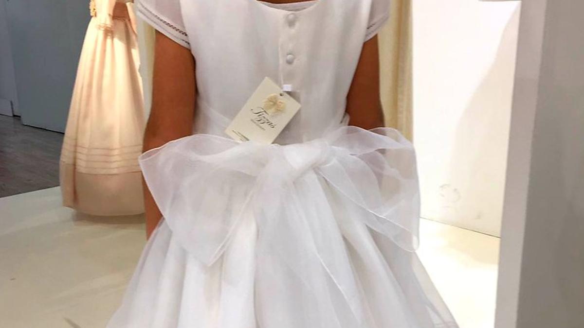 Una niña se prueba un vestido de comunión, en una tienda de Madrid