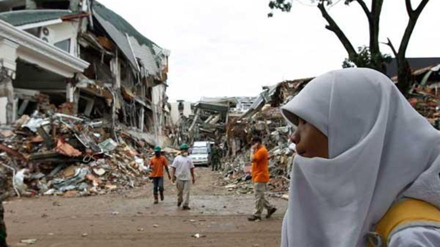 Una estudiante camina delante de unos edificios derruidos por el seismo