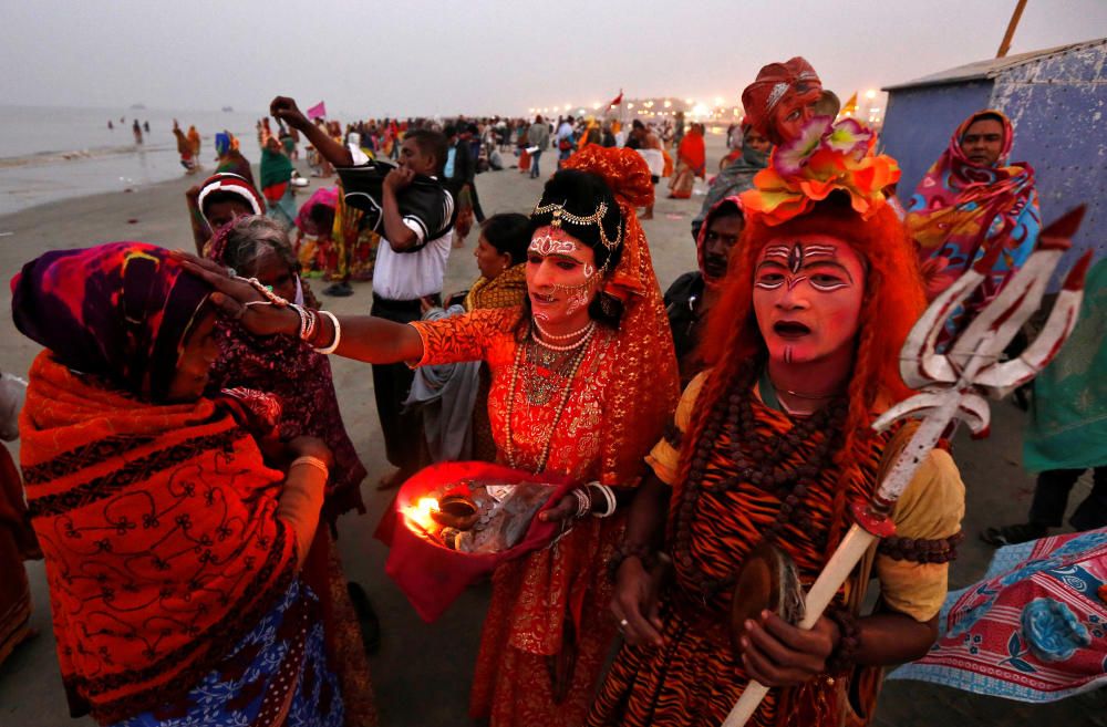 Dos indios vestidos como el dios Shiva y la diosa Parvati bendicen a un peregrino en el río Ganges, en Calcuta, India.