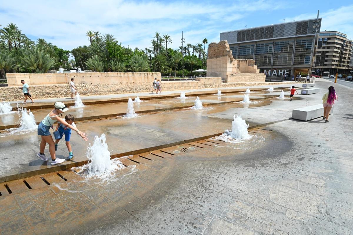 Varias personas se refrescan en una fuente en Elche