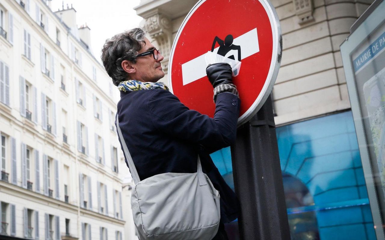 Clet Abraham, colocando uno de sus diseños en una señal en el centro de París.