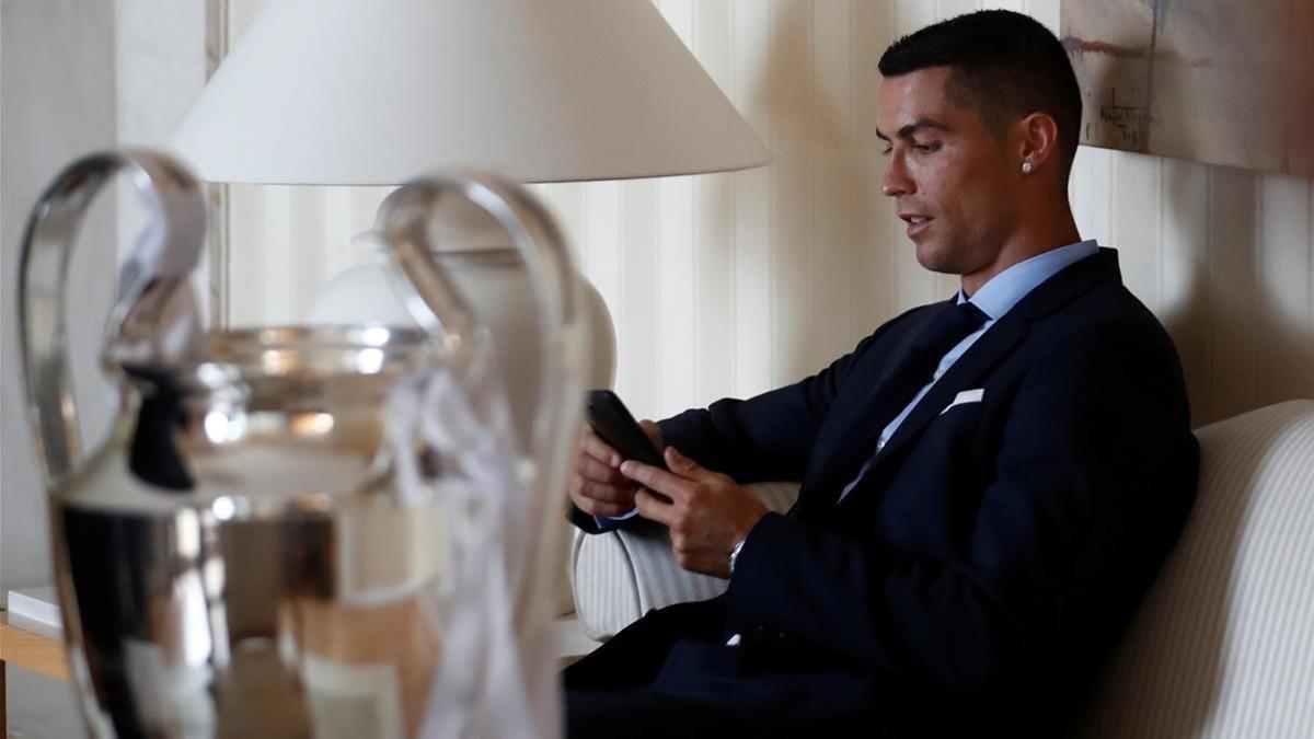 Cristiano Ronaldo mira su móvil durante la celebración de la Champions del Madrid.