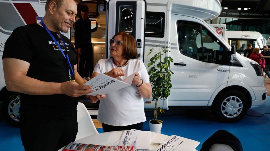 Dos personas ojean un folleto en uno de los stands montados en la última edición de la feria avilesina del campismo. | Mara Villamuza