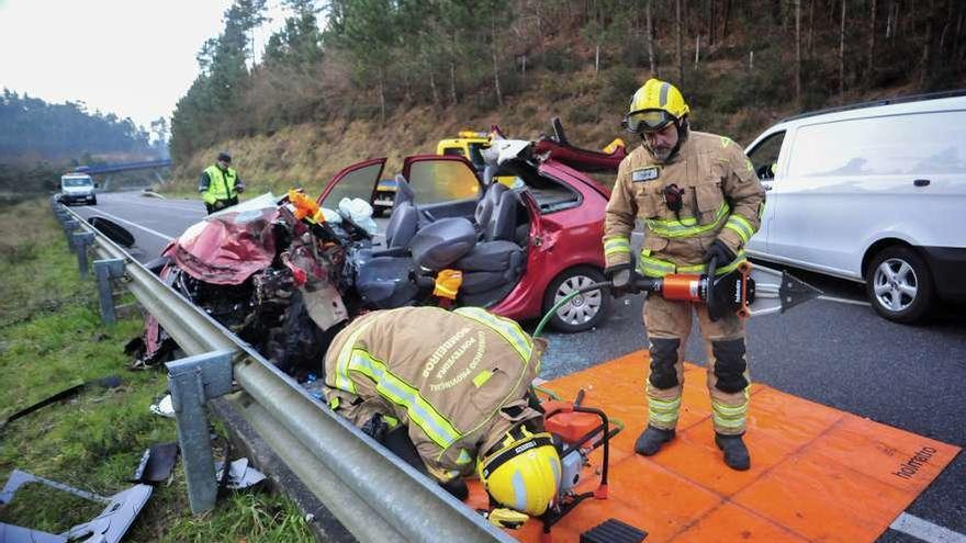 Los bomberos ante el coche en el que viajaba la víctima mortal y que tuvieron que excarcelar. // I. Abella