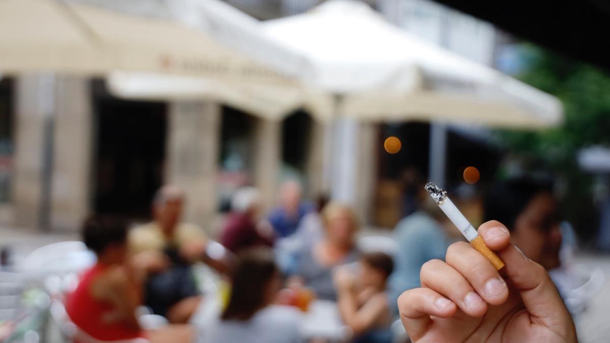 Un cliente fuma un cigarrillo en una terraza.