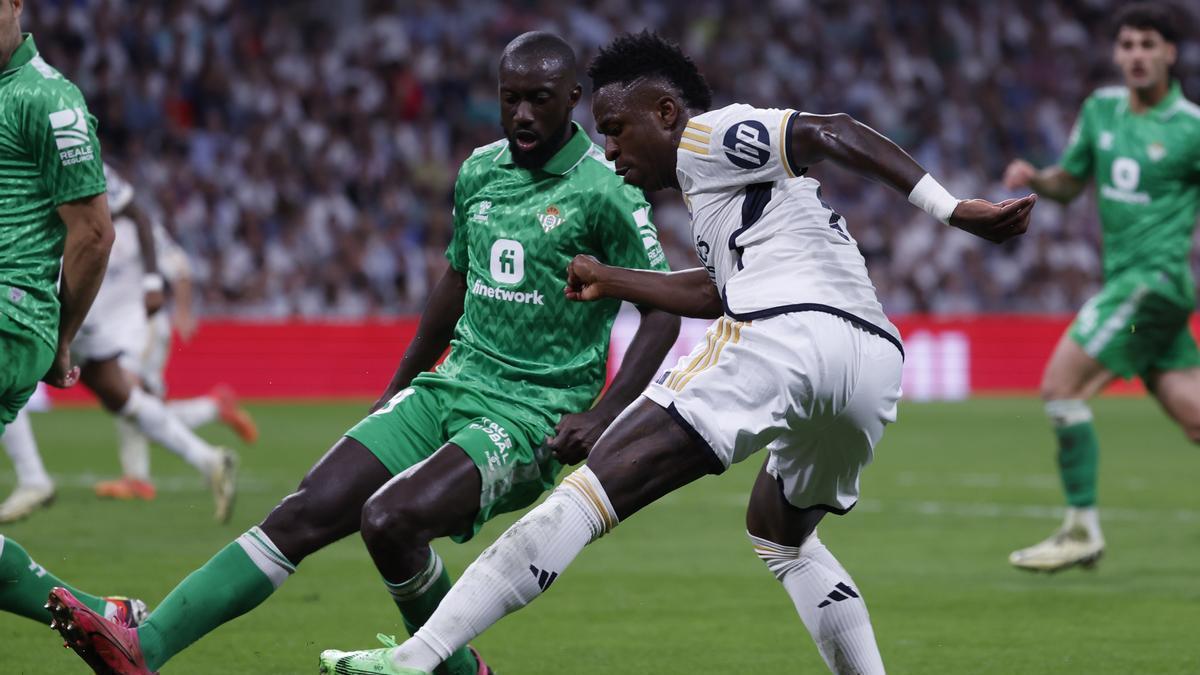 El delantero brasileño del Real Madrid Vinicius Jr. intenta superar a Youssouf Sabaly, del Betis, durante el partido de la jornada 38 de LaLiga que Real Madrid y Real Betis disputan hoy sábado en el estadio Santiago Bernabéu, en Madrid.