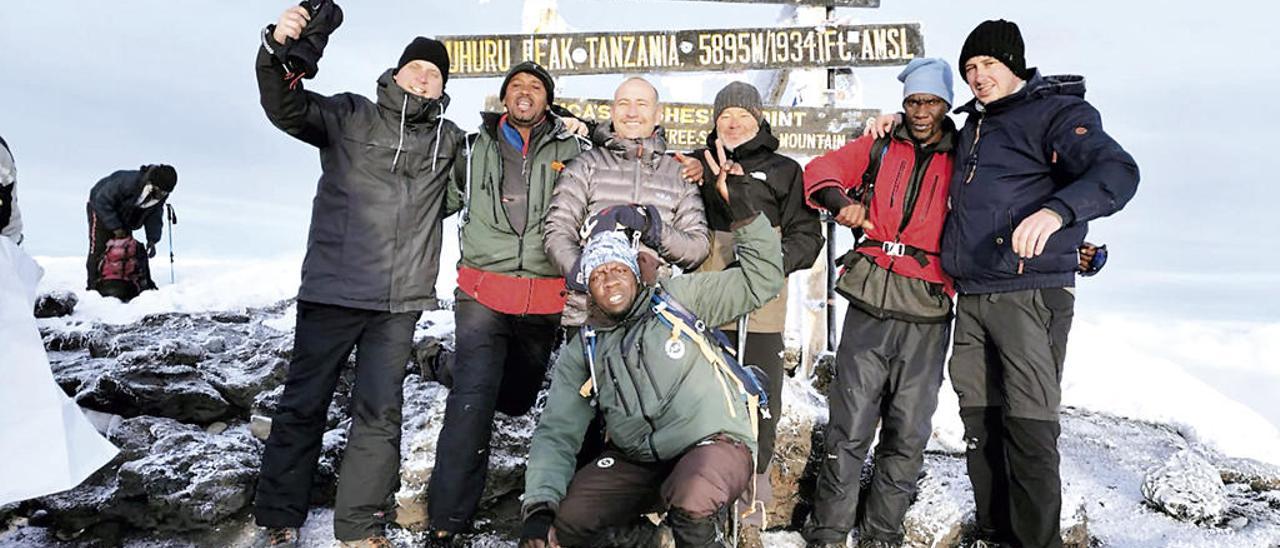 En la imagen superior, Silva (tercero por la izquierda) en la cima del Kilimanjaro. A la derecha, niños junto al pozo y el depósito de agua del colegio, en Moshi (Tanzania). // Cedidas