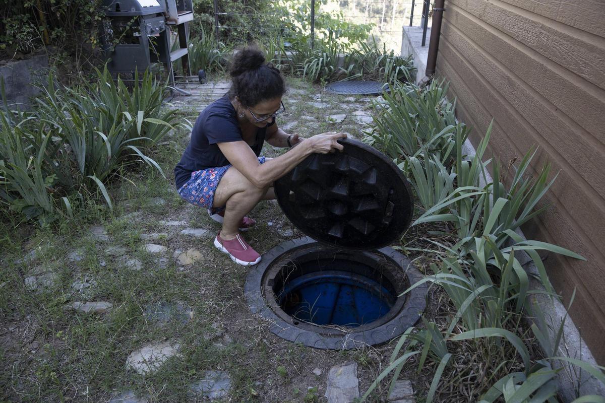 Ivanna Campos, vecina de Molins de Rei (Barcelona), muestra uno de los depósitos de agua de 7.000 litros recogida por la lluvia