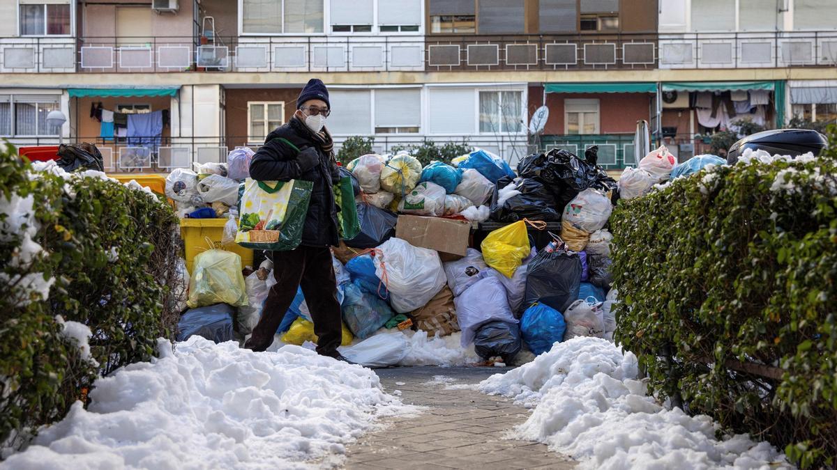 Decenas de bolsas de basura se acumulan en los cubos situados en las calles de Madrid tras las fuertes nevadas, el 13 de enero de 2021