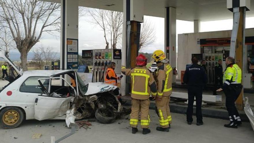 Els Bombers, al costat del cotxe sinistrat, que va xocar amb dues columnes i un vehicle de la benzinera