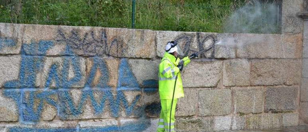 Operarios de FCC limpiando un muro en O Castro. // FdV