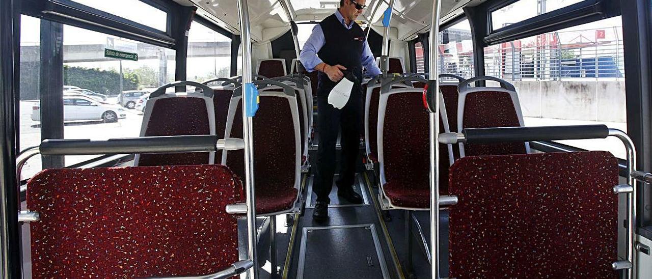 José Richart desinfecta barras y agarraderos del bus mientras espera viajeros en la estación.