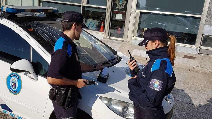 Dos agentes de la Policía Local de Cangas haciendo pruebas, ayer, con el etilómetro de precisión. // G.N.