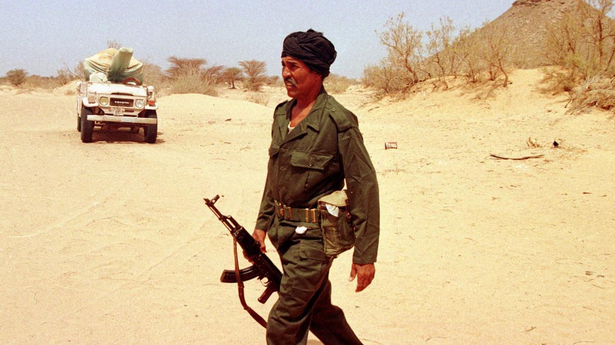 Un miembro de la guerrilla polisaria pasa junto a un vehículo con ametralladora tapada en algún punto ante el muro de Marruecos, el 26 de septiembre de 1997.