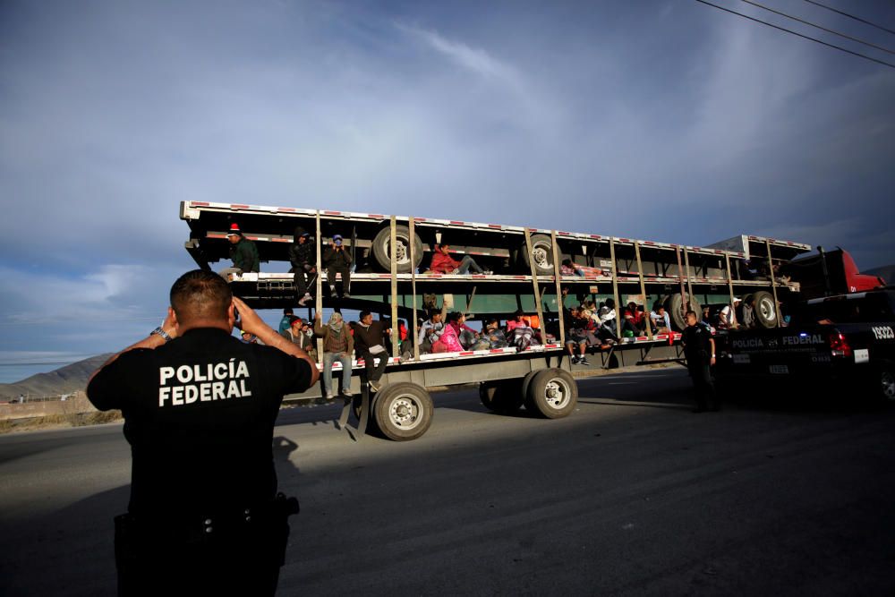 A police officer takes pictures of migrants as ...