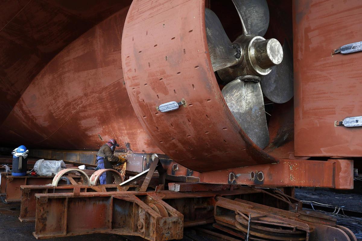 Un trabajador de un astillero trabajando en el casco de un barco