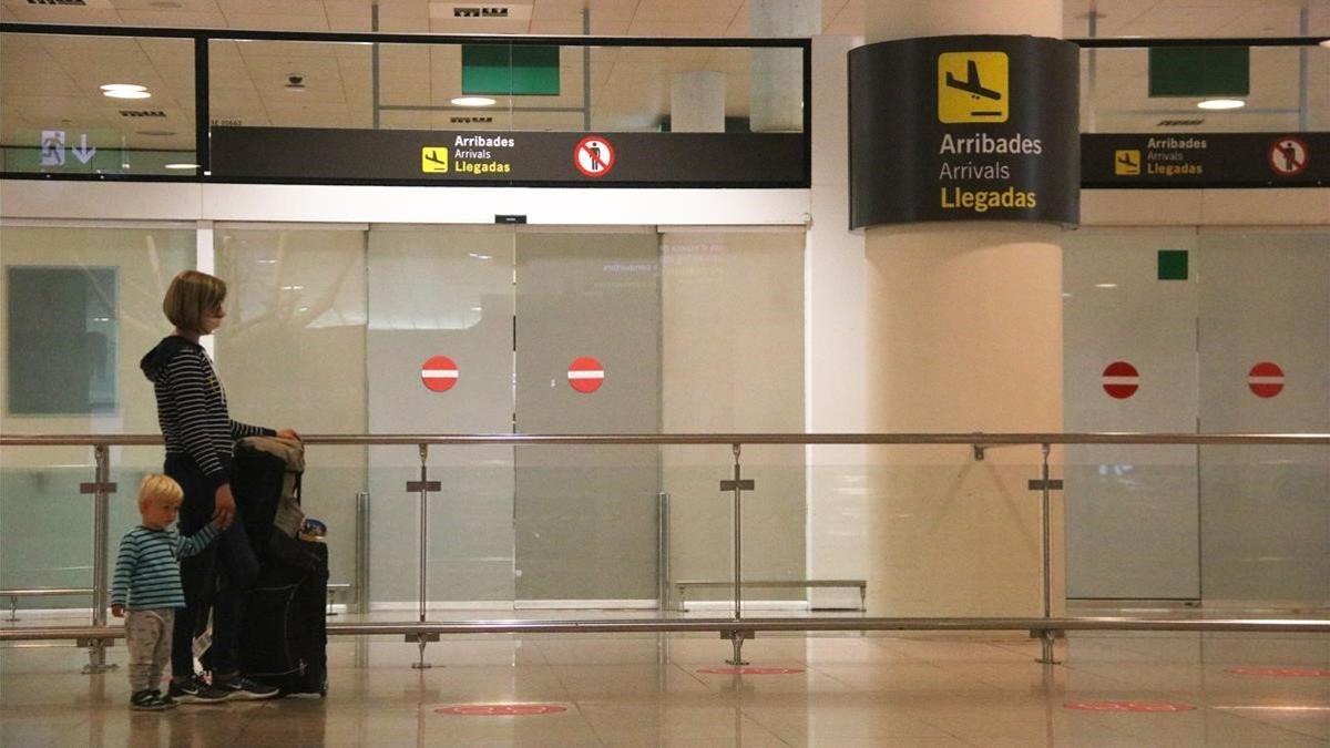 Una pasajera esperando en la terminal del aeropuerto de El Prat, este domingo