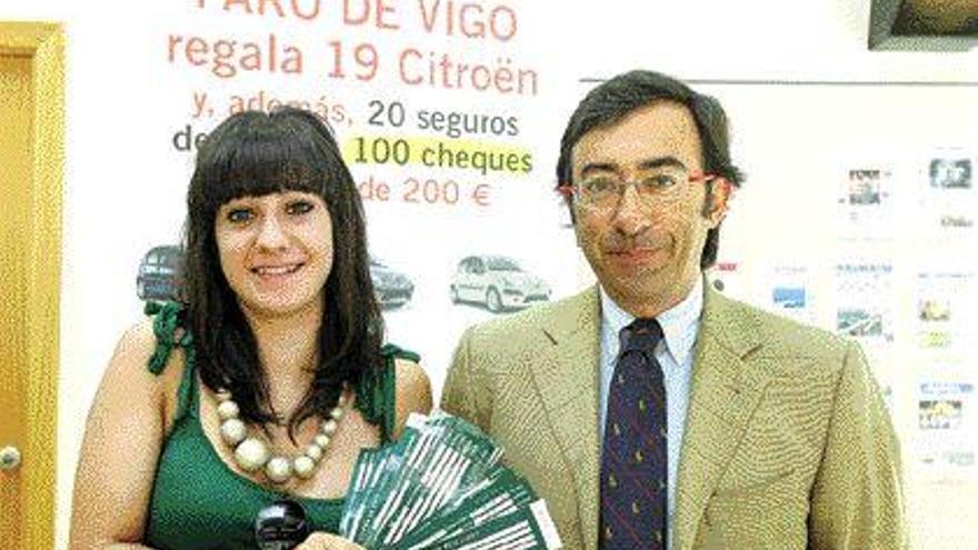 Lorena Neira, mano inocente del octavo sorteo, y el notario César Casqueiro muestran los resguardos. / JESÚS DE ARCOS