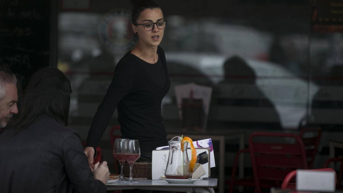 Archivo - Una camarera atiende la mesa de un bar en Sevilla. Imagen de archivo.