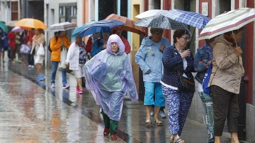 Un grupo de turistas, paseando bajo la lluvia, ayer, en Luanco.